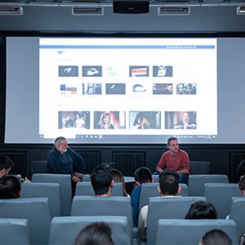 Una sala de conferencias con un grupo de personas frente a una pantalla que muestra contenido en una presentación.