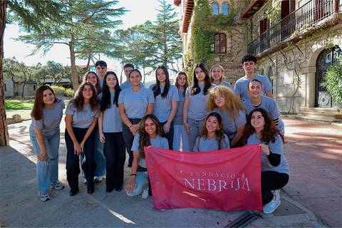 Un grupo de jóvenes estudiantes posando en un entorno natural con una pancarta de la Fundación Nebrija.