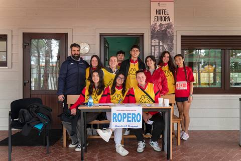Un grupo de jóvenes sonrientes posan en un ambiente al aire libre, junto a una mesa con un cartel que dice 'ROPERO'.