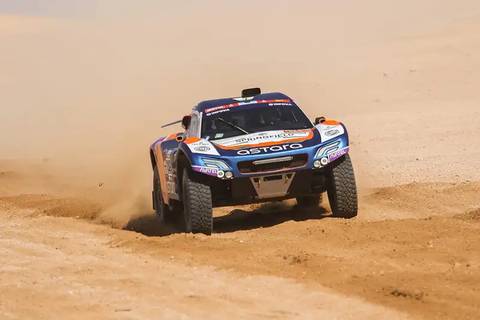 Un automóvil de carreras especializado en terrenos áridos derrapando en una pista de arena.