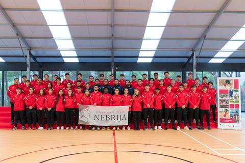 Grupo de estudiantes de la Universidad Nebrija uniformados en rojo, posando en un gimnasio.