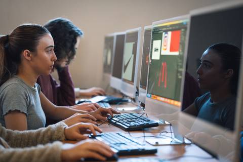 Un grupo de estudiantes está trabajando en ordenadores en un aula de informática.
