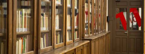 Un pasillo con estanterías de madera llenas de libros y una puerta al fondo.