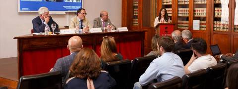 Una presentación en un evento con varios oradores y un público atento.