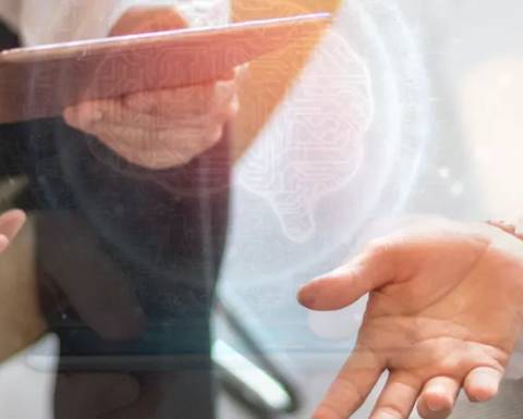 Una mano sostiene una tablet mientras otra mano está extendida, con un fondo que sugiere tecnología avanzada.