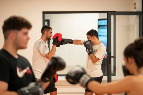 Un grupo de personas entrenan boxeo en un gimnasio.