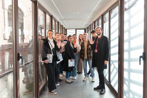 Grupo de personas sonriendo y saludando en un pasillo iluminado.