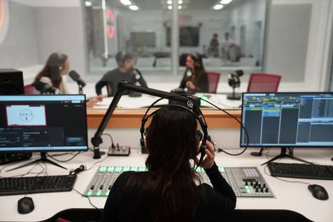 Un grupo de personas interactúa en un estudio de grabación de radio.