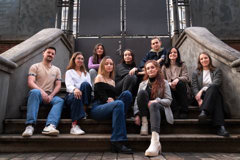 Un grupo de diez personas posando en una escalera al aire libre.