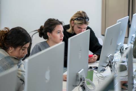 Un grupo de personas trabajando en computadoras en un espacio de estudio.