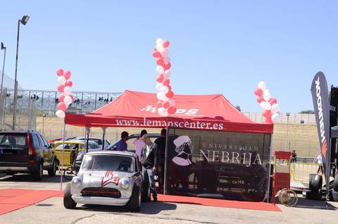 Una carpa con globos y un coche clásico en un evento automovilístico.