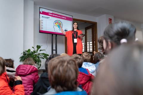 Una presentadora explica un tema a un grupo de niños en un aula.