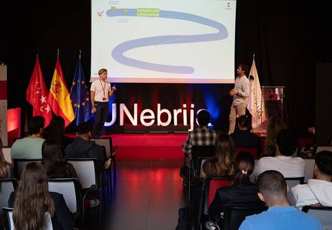 Una presentación en una conferencia con dos ponentes y un público atento.