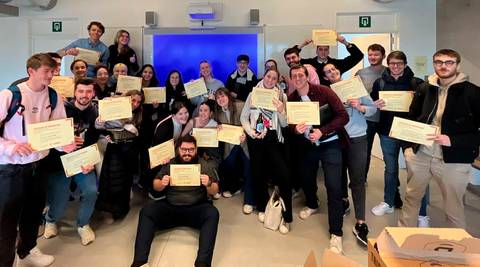Grupo de personas sonrientes sosteniendo certificados en un ambiente festivo.