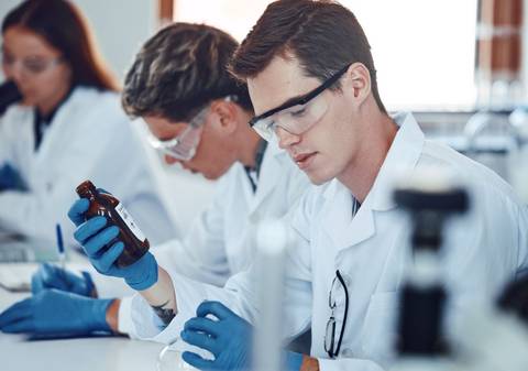 Un grupo de estudiantes de laboratorio trabaja en experimentos científicos con frascos y herramientas de laboratorio.