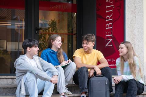 Un grupo de cuatro estudiantes conversando en la entrada de una universidad.