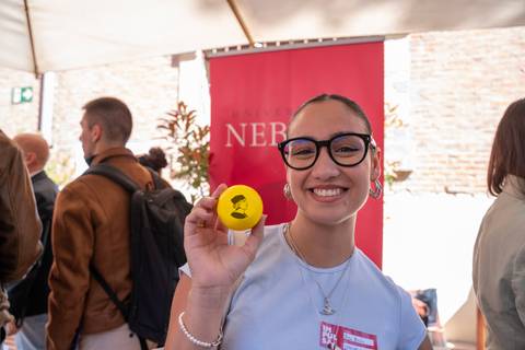 Una joven sonriente sostiene una pelota amarilla mientras se encuentra en un evento social.