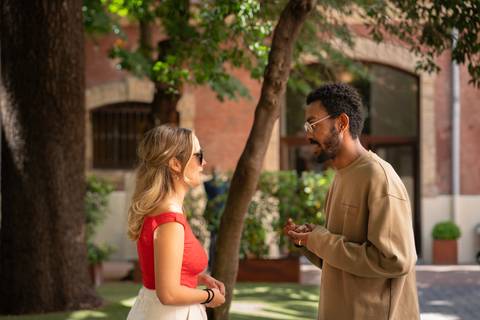 Una pareja de personas conversando en un entorno al aire libre con árboles y plantas.