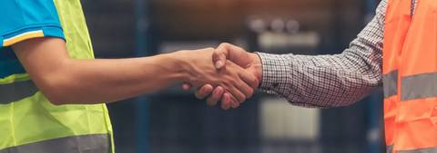 Dos personas se dan la mano en un ambiente laboral.