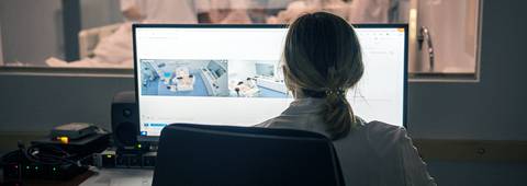 Una persona observa pantallas de monitoreo en un entorno médico.