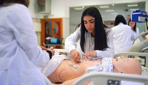 Una estudiante de medicina practica procedimientos médicos en un maniquí en un entorno de simulación.