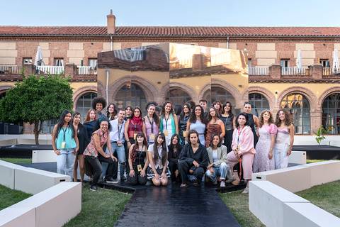 Un grupo de mujeres posando juntas en un evento al aire libre en un entorno arquitectónico histórico.