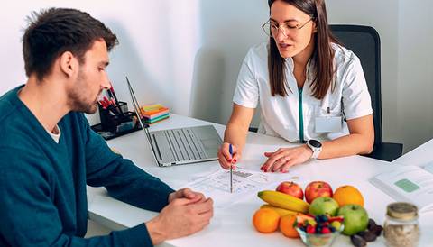 Una doctora conversa amablemente con un paciente en un consultorio médico.