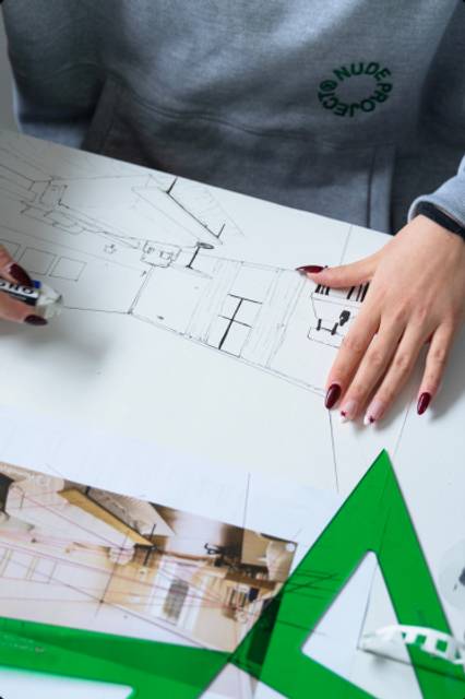 Una persona dibuja planos arquitectónicos sobre una mesa.