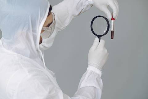 Un científico examina una muestra de sangre con una lupa.