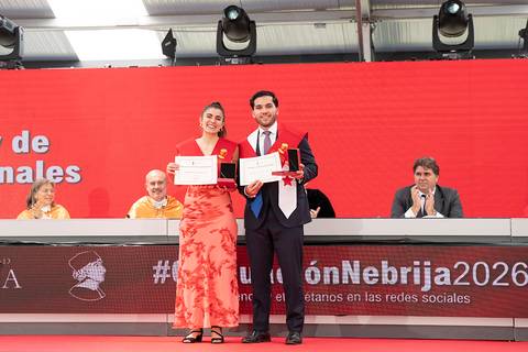 Dos graduados posan con sus certificados en un evento de premiación.