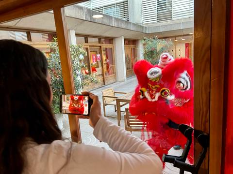 Una persona está grabando con su teléfono a un espectáculo de danza tradicional que presenta un disfraz rojo y enérgico.