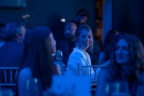 La imagen muestra a un grupo de personas conversando en un ambiente iluminado con tonos azules.