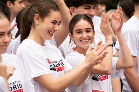 Un grupo de jóvenes en camiseta blanca sonríen y aplauden durante un evento.