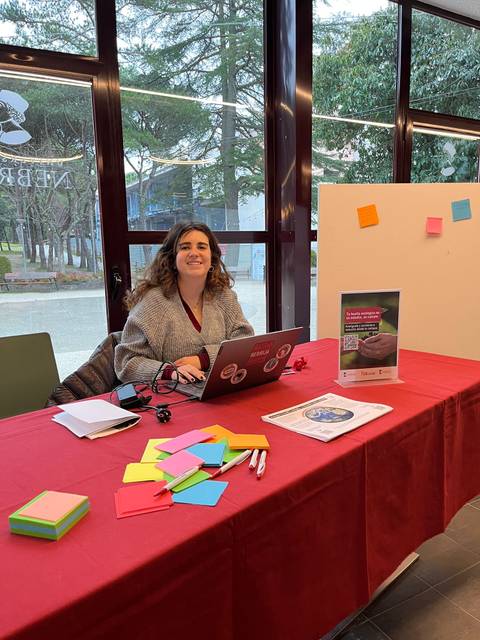 Una persona sonriente trabaja en una mesa con post-its de colores y una computadora portátil.