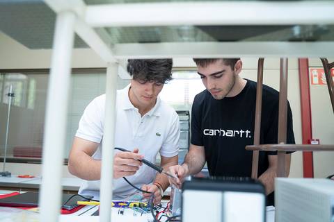 Dos jóvenes trabajan juntos en un proyecto de electrónica en un laboratorio.