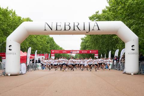 Un grupo de corredores inicia una carrera bajo un arco inflable con la palabra 'NEBRIJA'.