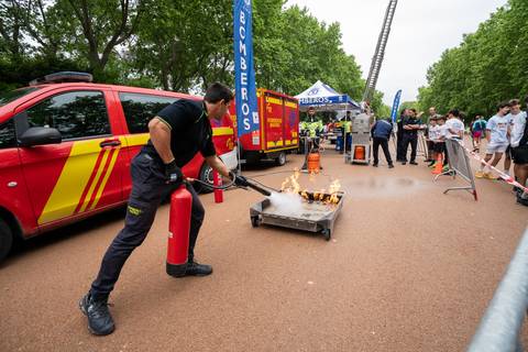 Un bombero apaga un fuego controlado utilizando un extintor en un evento al aire libre.