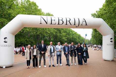 Un grupo de personas posando frente a un arco decorativo con la palabra 'NEBRIJA' en un evento al aire libre.