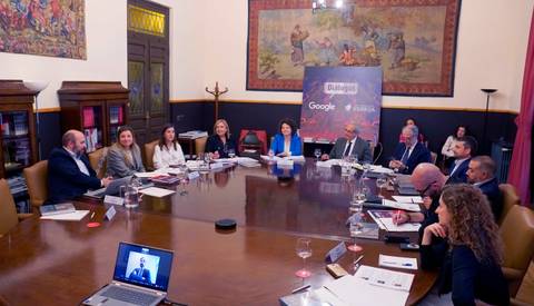 Reunión en una sala con un gran mesa ovalada y participantes discutiendo temas importantes.