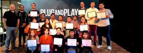 Un grupo de personas posan juntas sosteniendo certificados en un evento de Plug and Play.