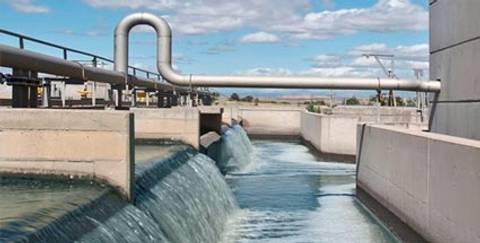 La imagen muestra una planta de tratamiento de agua con tuberías y un flujo de agua visible.