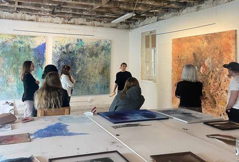 Una artista explica su obra a un grupo de personas en una galería de arte.