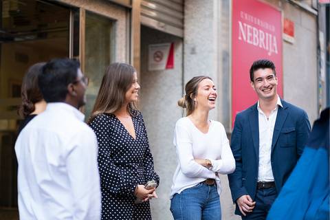 Un grupo de jóvenes sonrientes conversando animadamente en la calle.