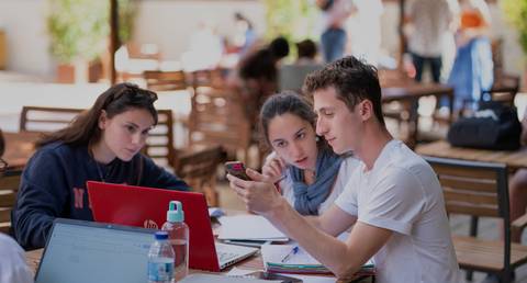 Tres estudiantes colaboran en un ambiente de estudio al aire libre.
