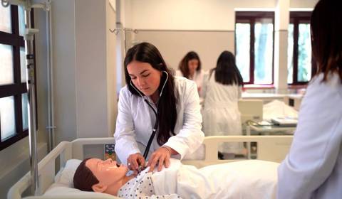 Una estudiante de medicina examina a un maniquí en un aula de simulación médica.