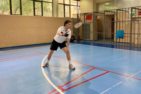 Un jugador de bádminton realizando un golpe en una cancha interior.