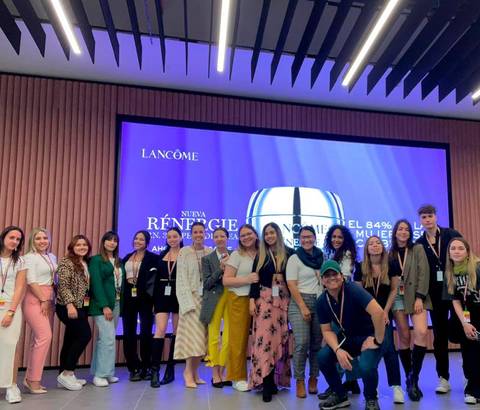 Un grupo de personas posando frente a un fondo promocional de la marca Lancôme.