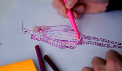 Un boceto de moda en el que se está dibujando un vestido con lápices de colores.