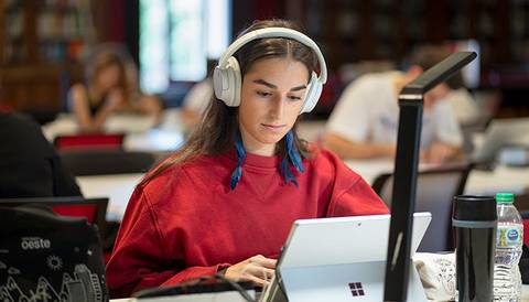Una joven con auriculares estudia con una tablet