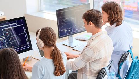 Un grupo de estudiantes trabajando en computadoras en un entorno educativo.